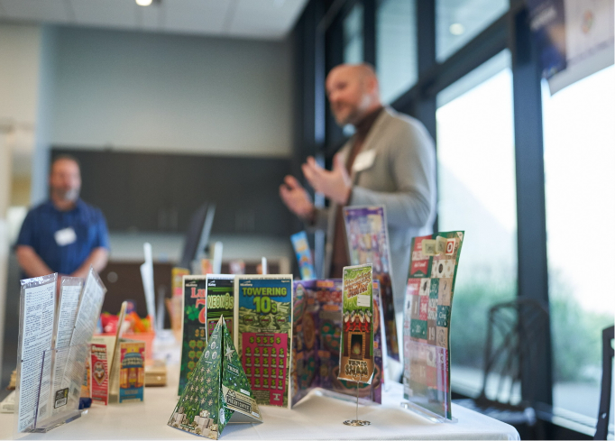 person giving a presentation in front of a table with a table with a series of instant tickets